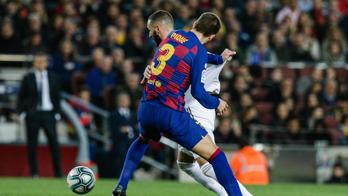 Gerard Piqué pugna por un balón con Karin Benzema.