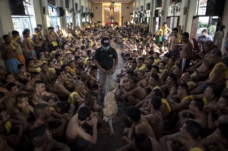 Decenas de presos se sientan en el suelo de una cárcel de Manila mientras un miembro de la brigada filipina antidroga busca material de contrabando. AFP PHOTO / Noel CELIS