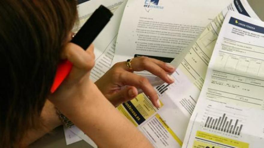 Una mujer consulta varios recibos de la luz.