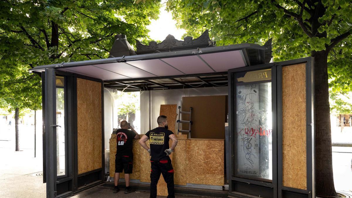 Dos operarios retiran el mobiliario del quiosco de Zaragoza donde iba a instalarse una churrería.