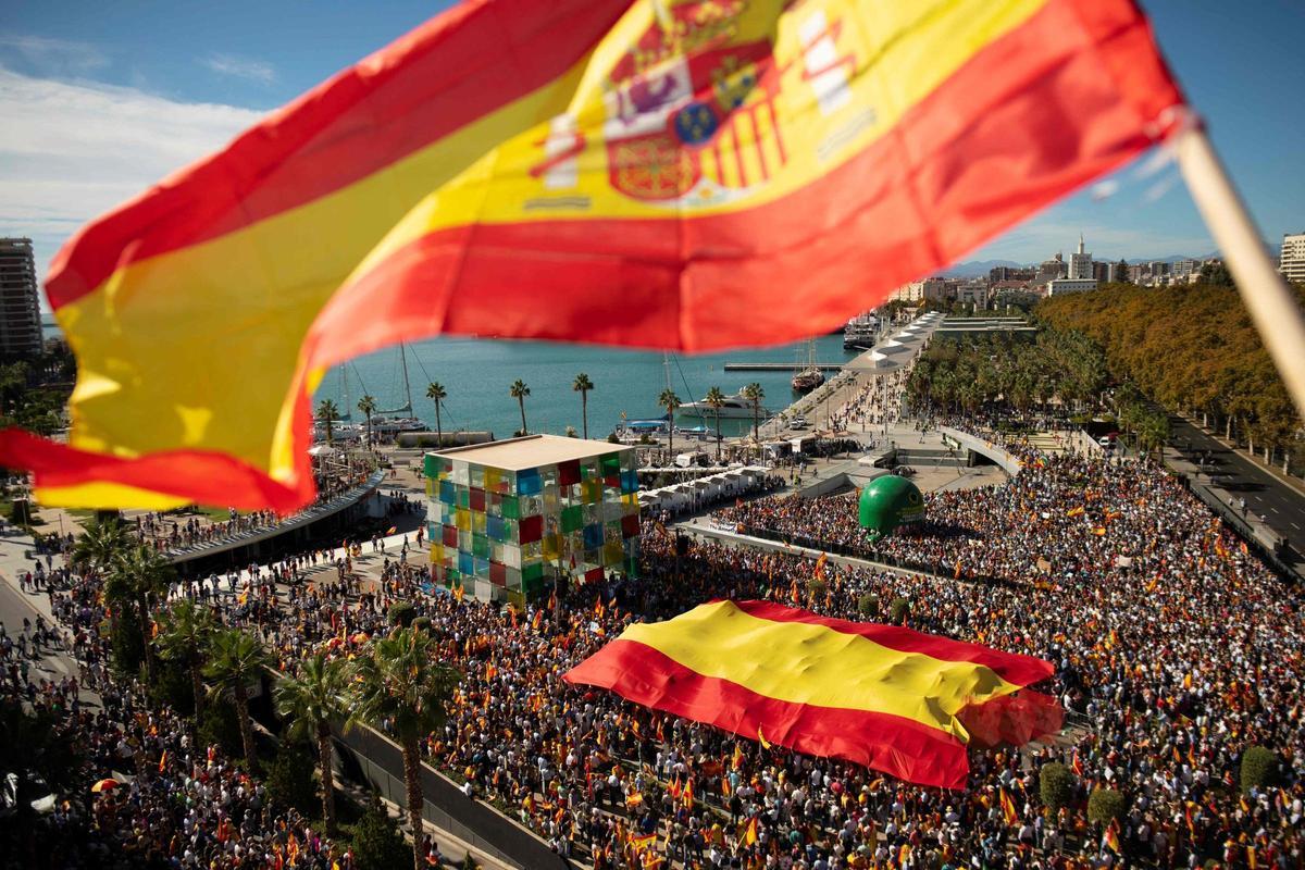 Los manifestantes marchan con una bandera gigante en Málaga durante una protesta convocada por la oposición de derecha contra un proyecto de ley de amnistía para las personas involucradas en el fallido intento de independencia de Catalunya de 2017, el 12 de noviembre de 2023.