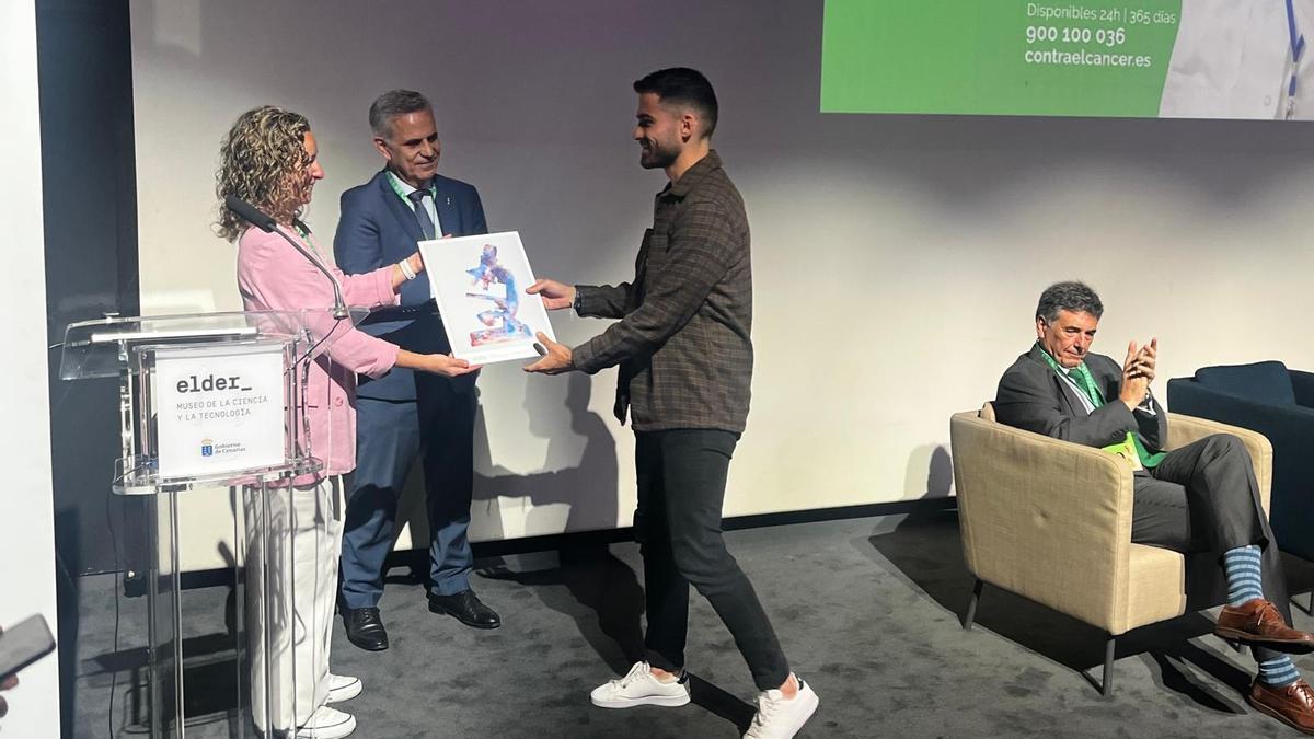 Silvio Galeano, investigador becado por la Asociación Española contra el Cáncer en Canarias, recibe un diploma honorífico.