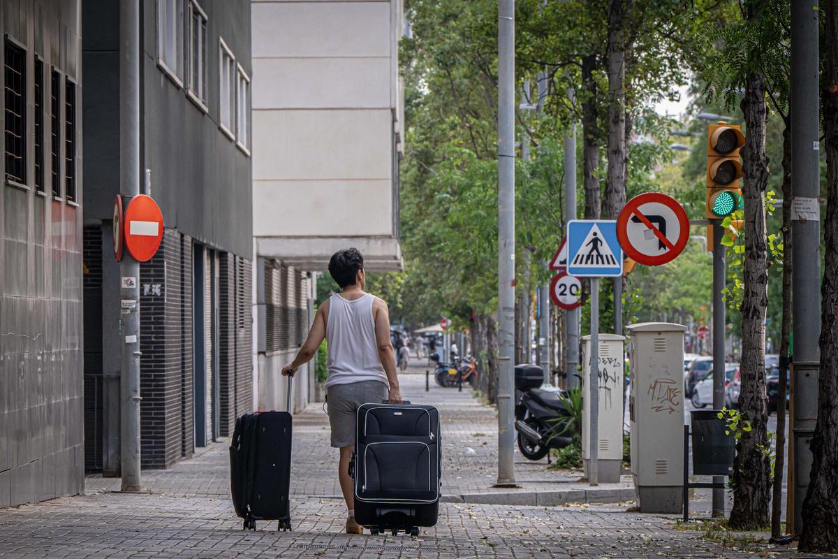 Una persona cargada con dos maletas en el barrio de La Mina, en Sant Adrià de Besòs.
