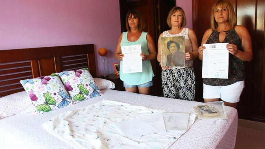 Las hermanas Agulló posan con una foto de su madre y una mantita que pertenecía a su hermana Rocío, a la que buscan ahora.