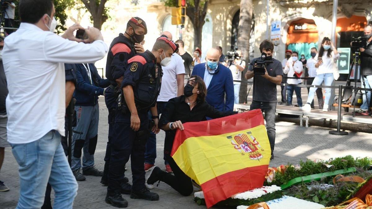 Un periodista de un canal de televisión, frente al monumento con una bandera española, buscando la provocación.