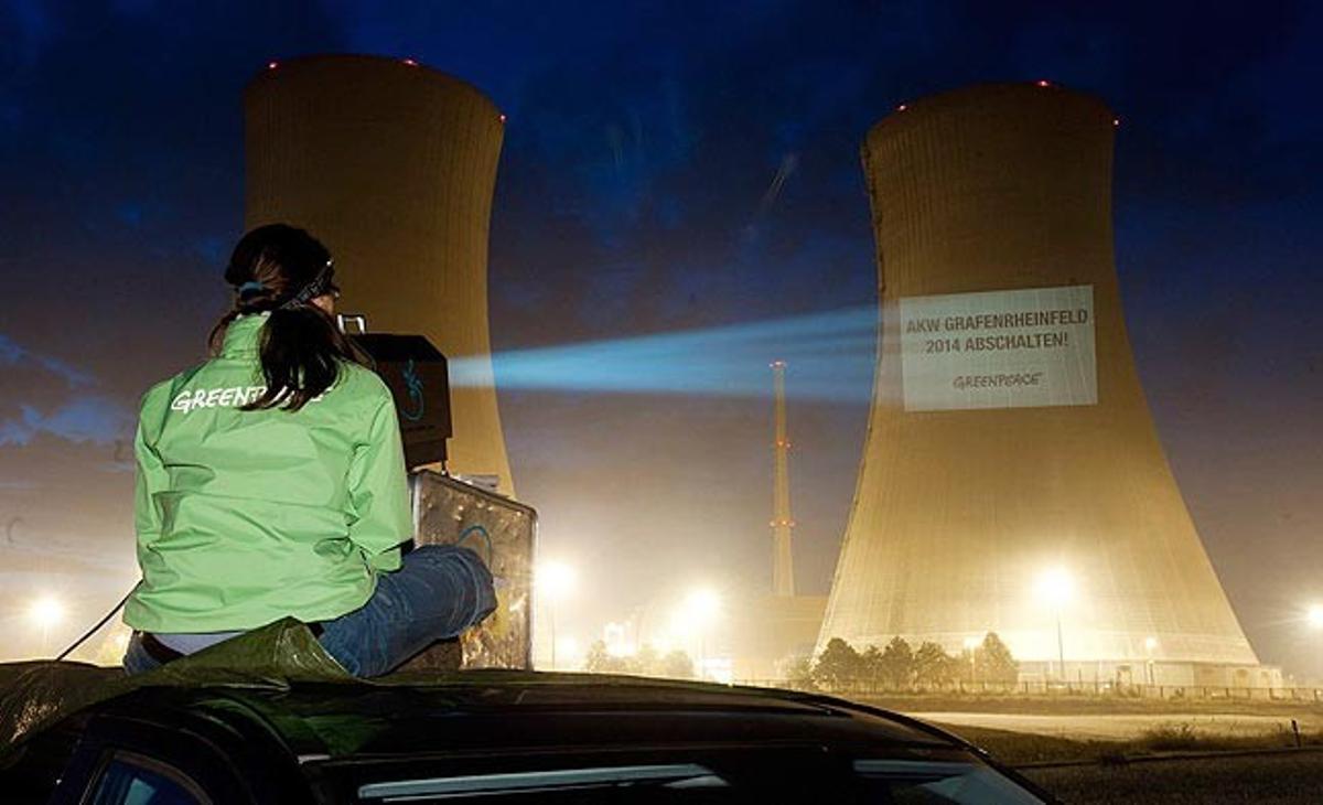 Una activista de Greenpeace projecta aquest dilluns un missatge en una torre de refrigeració de la planta nuclear de Philippsburg (Alemanya) en què es pot llegir ’Planta nuclear de Philippsburg 2- apagada el 2013’.