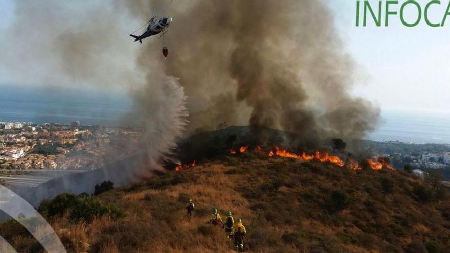 Varios operarios del Infoca y un helicóptero trabajan en el lugar del incendio.