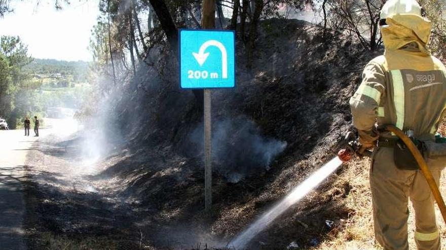 Un bombero riega la zona hacia la carretera. // Bernabé/Noelia Porta