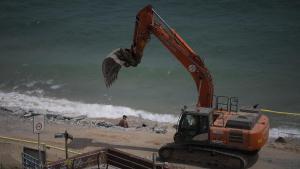 Una retroexcavadora trabaja, ya entrada la temporada de baño, en la playa de Montgat, el municipio metropolitano cuyo litoral ha sido el más castigado por los últimos temporales