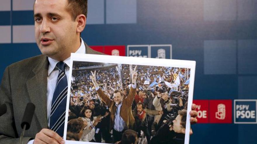 Jorge Alarte muestra una foto en la que puede verse al líder del PP Mariano Rajoy junto a &quot;el bigotes&quot; durante un mitin en Valencia