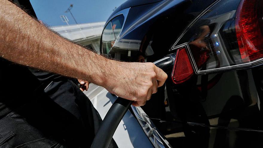 Una persona recarga un coche eléctrico en un punto de recarga.