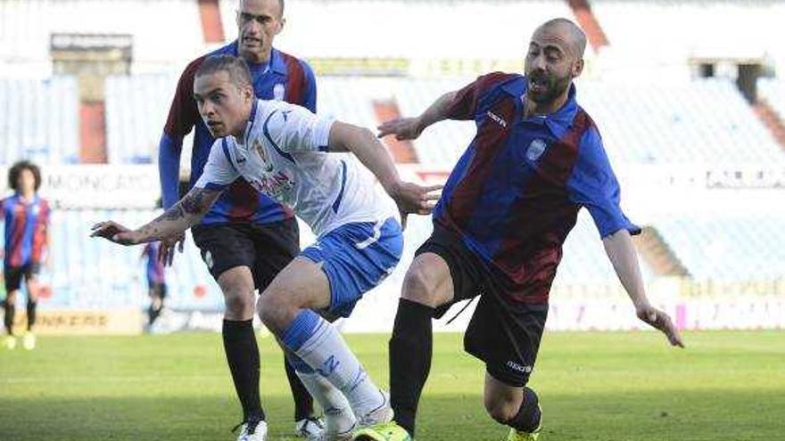 El azulgrana José Sánchez disputa un balón a un jugador zaragozano en La Romareda.