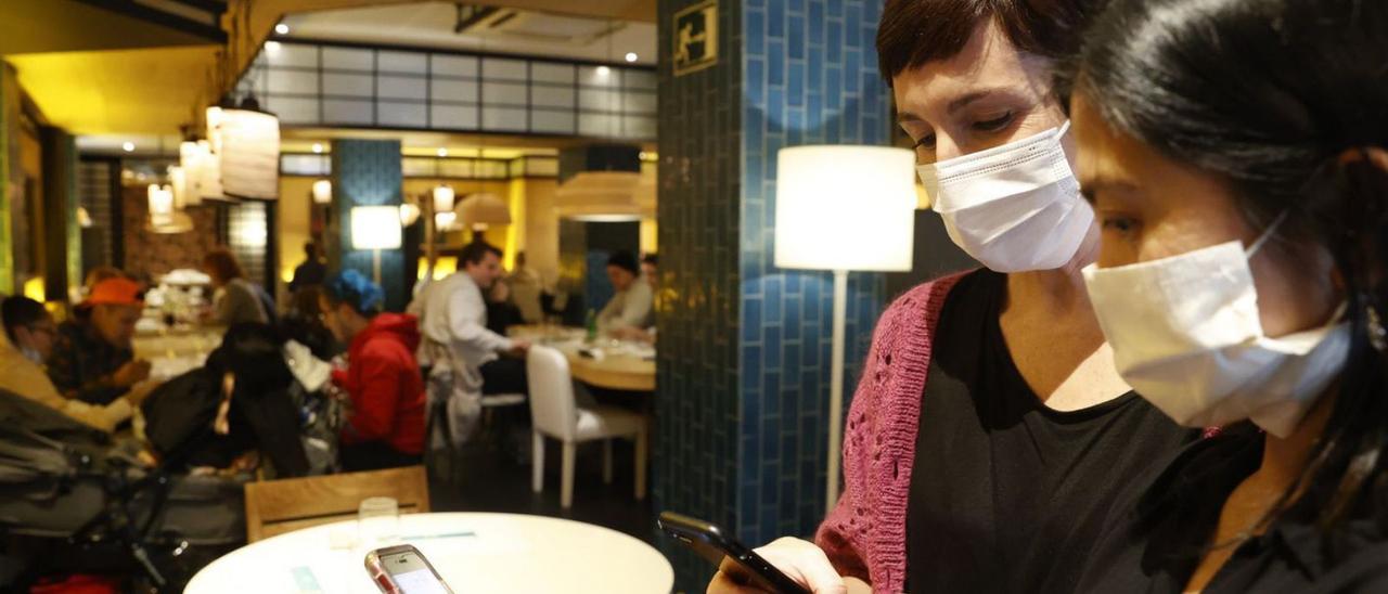 Una joven con mascarilla muestra el certificado COVID a la camarera de un restaurante cuando aún estaba en vigor esa exigencia en la hostelería.  | // LUIS TEJIDO