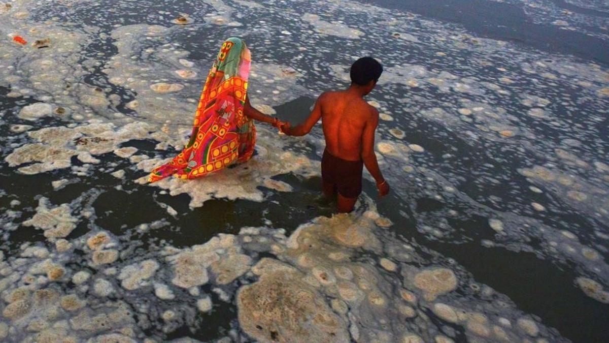 Dos hindús se bañan en las ocntmainadas aguas del río Ganges para lavar sus pecados.