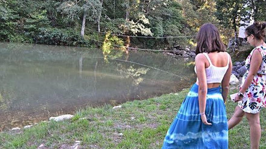 Dos jóvenes observan el agua afectada por el vertido en la playa fluvial de Lubián