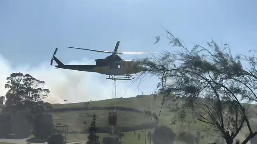 Un helicóptero retira agua en el parque de Bens durante la extinción de un fuego forestal