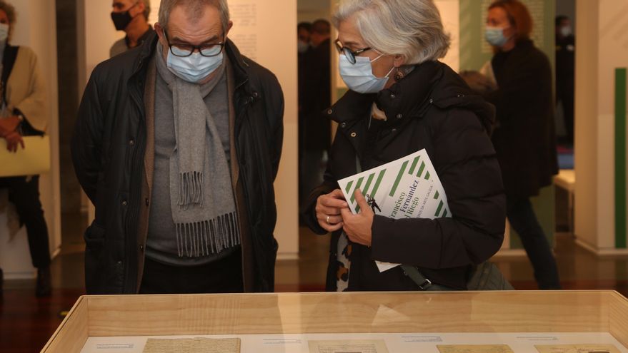 Dúas persoas contemplan varios documentos da exposición.