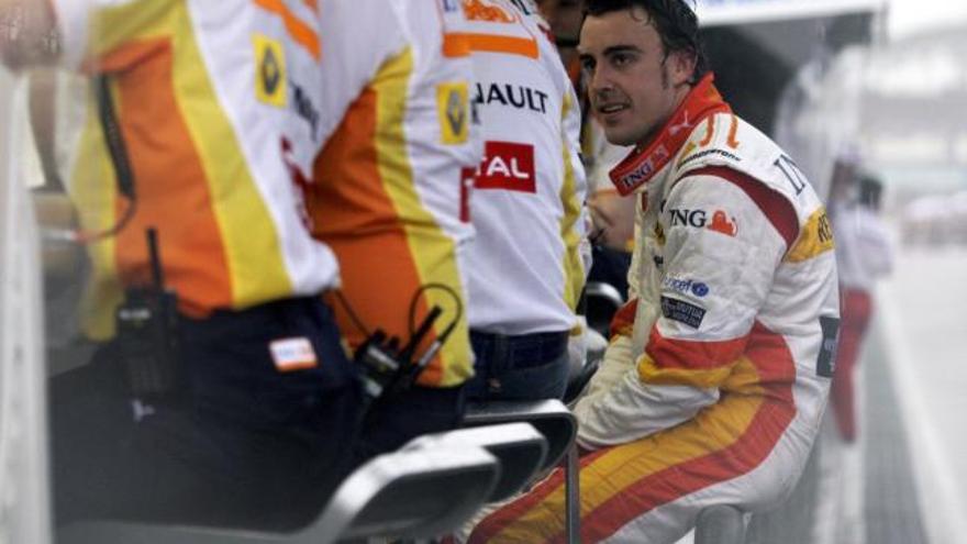 El piloto español de Fórmula 1 Fernando Alonso, de la escudería Renault, conversa con técnicos del equipo durante la tormenta que obligó a detener el Gran Premio de Malasia.