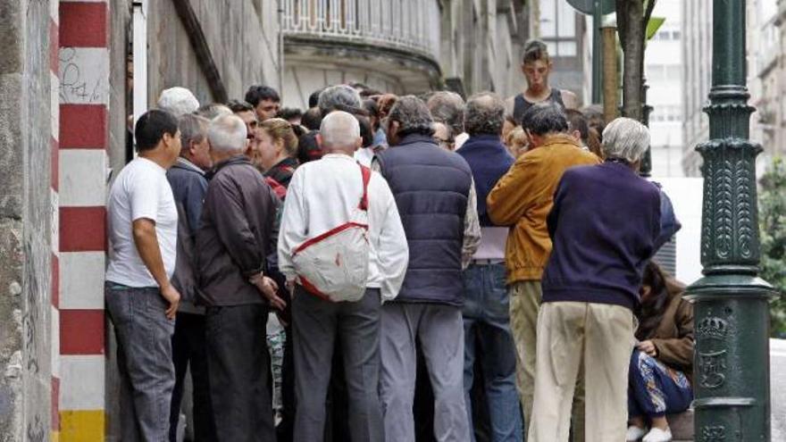 Un grupo de personas hace cola a las puertas de un comedor social gallego. / marta g. brea