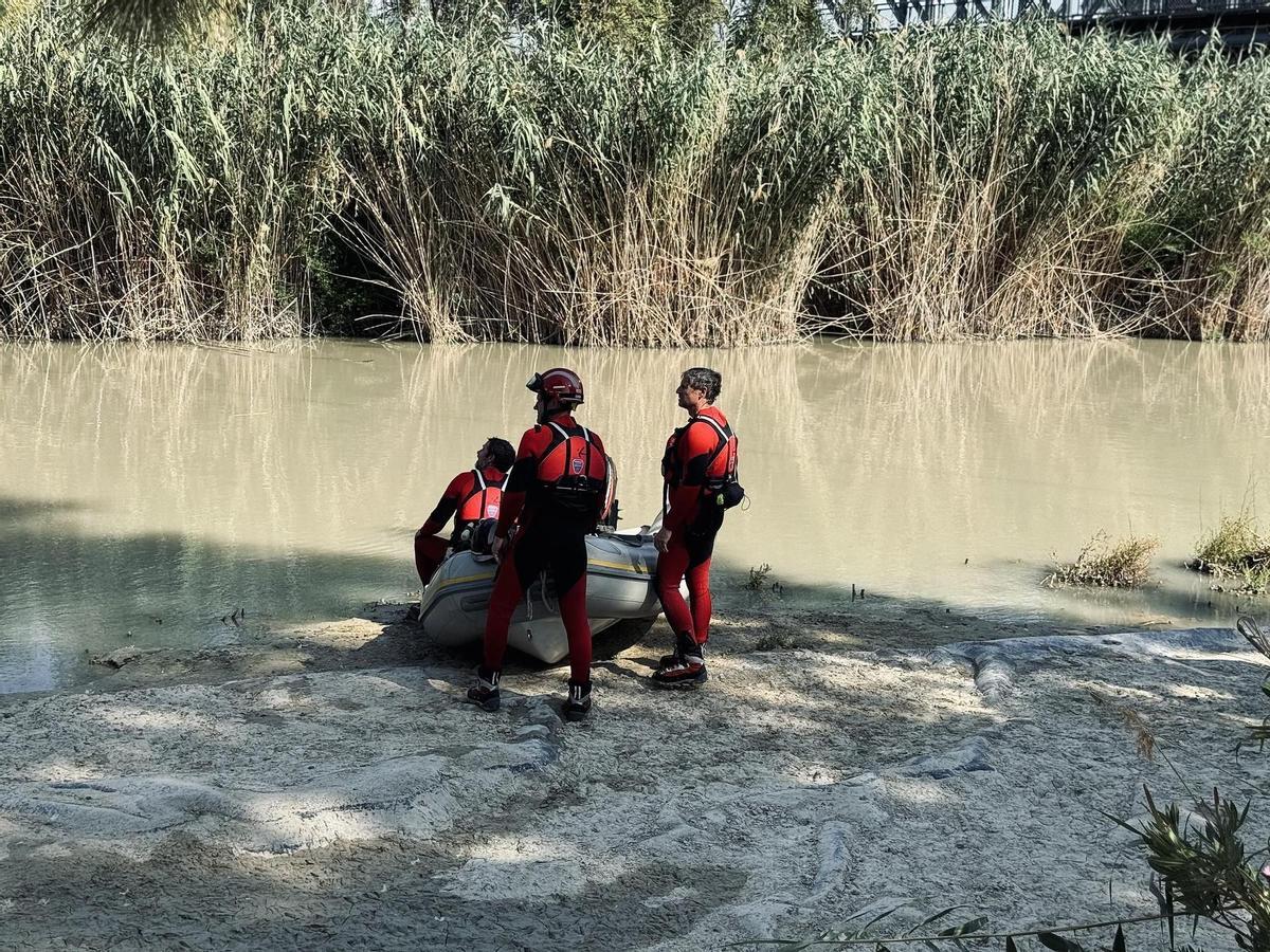 Efectivos, a pie de río, con una embarcación, durante la búsqueda.