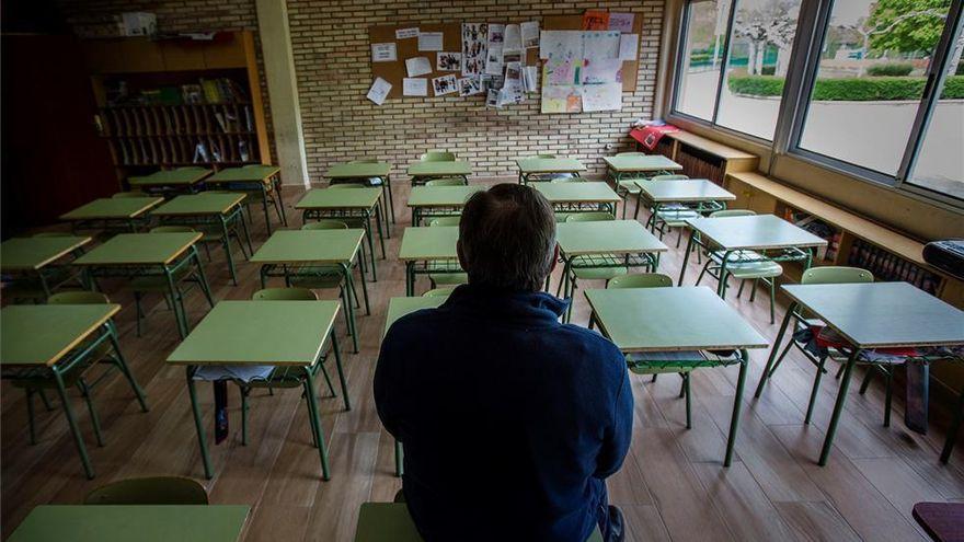 Un profesor, de espaldas, en un aula vacía.