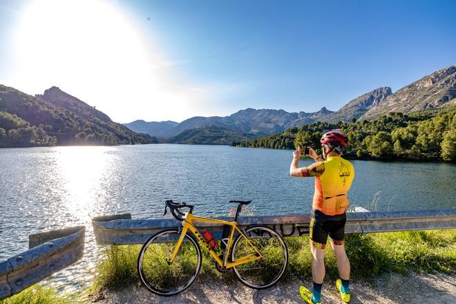 Un ciclista toma una imagen con su teléfono del pantano de Guadalest lleno