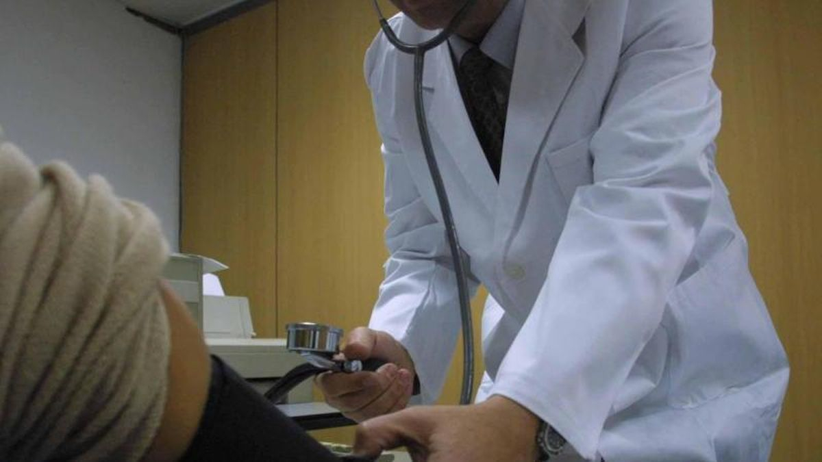 Un médico toma la tensión a una paciente durante una consulta.