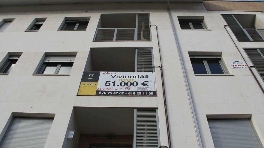 Edificio con un cartel anunciando la venta de pisos en Llanes.