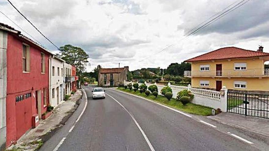 Tramo sin aceras de A Patiña y, al fondo, casa en ruinas.