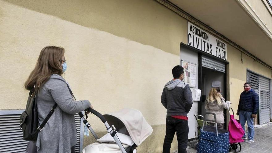 Vecinos esperando a las puertas de la asociación para recibir alimentos.