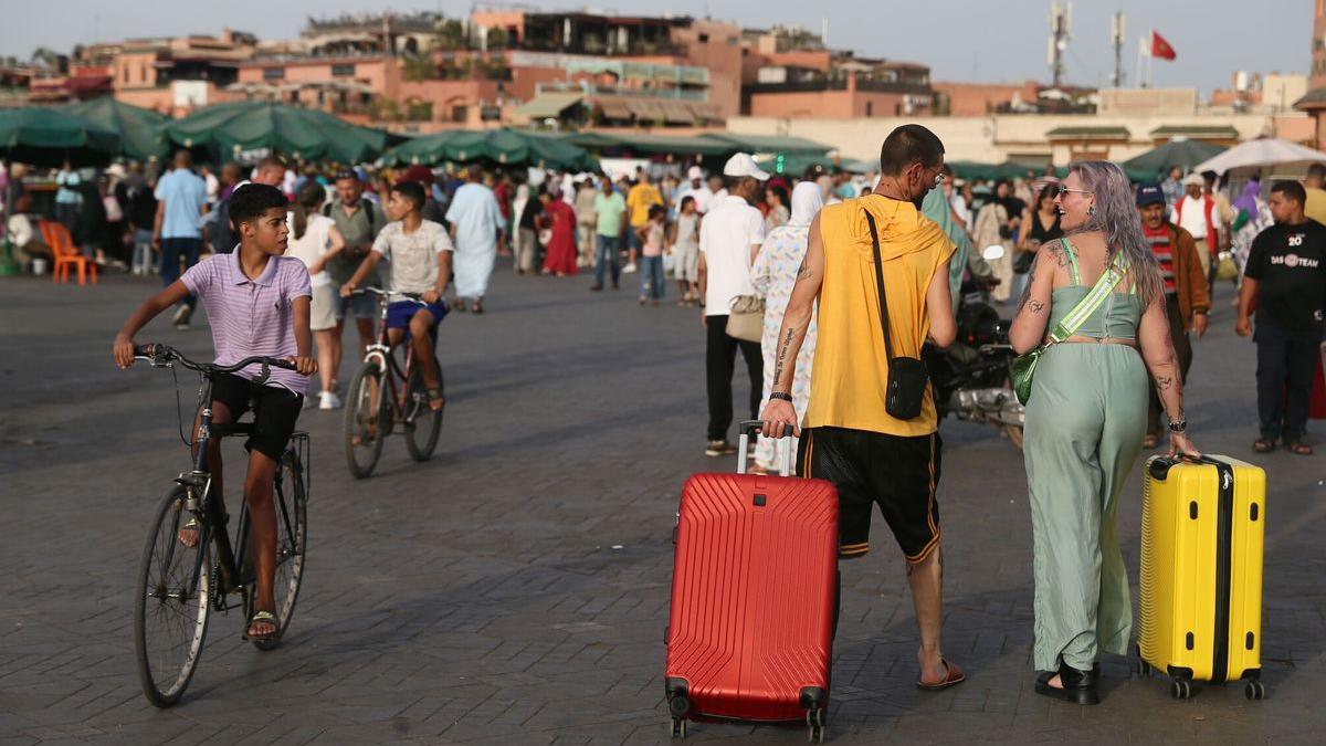 Una pareja de turistas arrastra sus maletas por la plaza de Yamaa el Fna de Marrakech, en Marruecos.