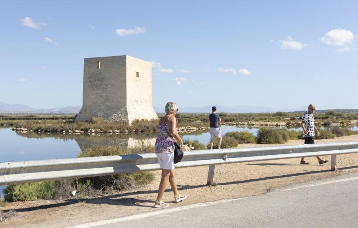 Turistas extranjeros junto a la Torre del Tamarit en el espacio protegido de la Salinas de Santa Pola. | ÁLEX DOMÍNGUEZ