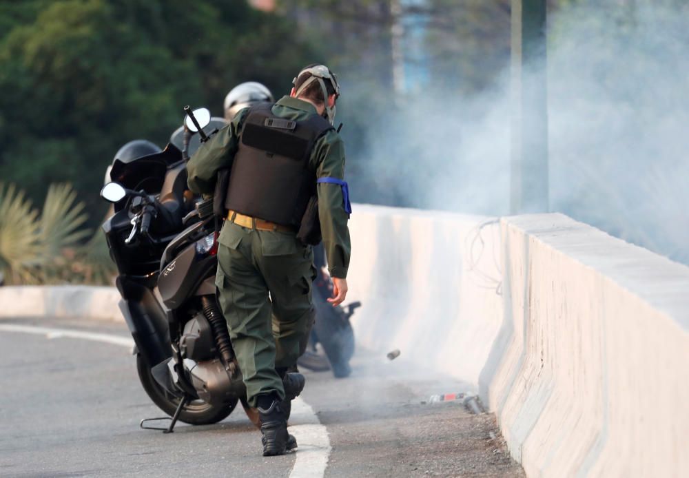 A military member kicks a tear gas canister near ...