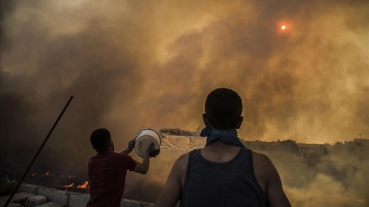 Personas intentan apagar el fuego en las tierras de cultivo que rodean la ciudad de Qamishli, en el noreste de Siria.