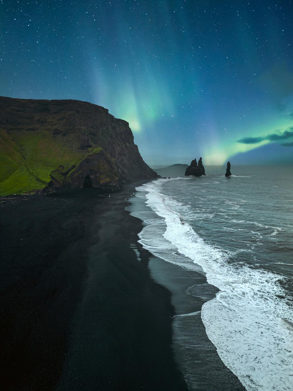 Auroras boreales sobre la playa de arena negra Reynisfjara