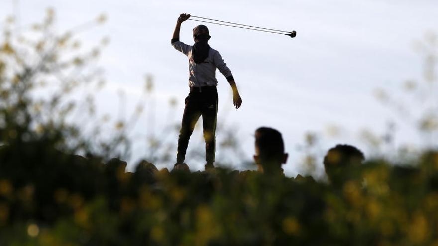 Un palestino se prepara para lanzar una piedra a soldados israelíes.