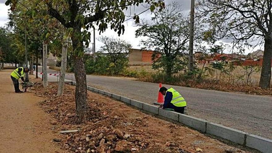 Dos trabajadores acometen los trabajos de prolongación de una acera en el paseo del Canto.