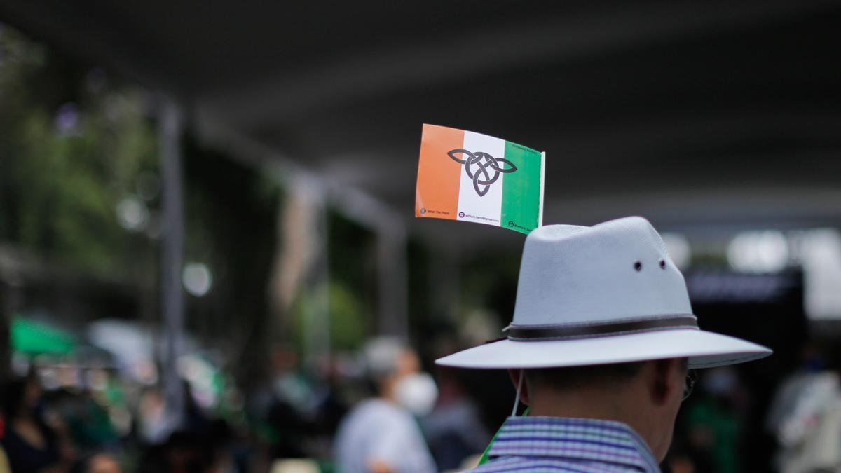 Un hombre con una bandera irlandesa en su sombrero.