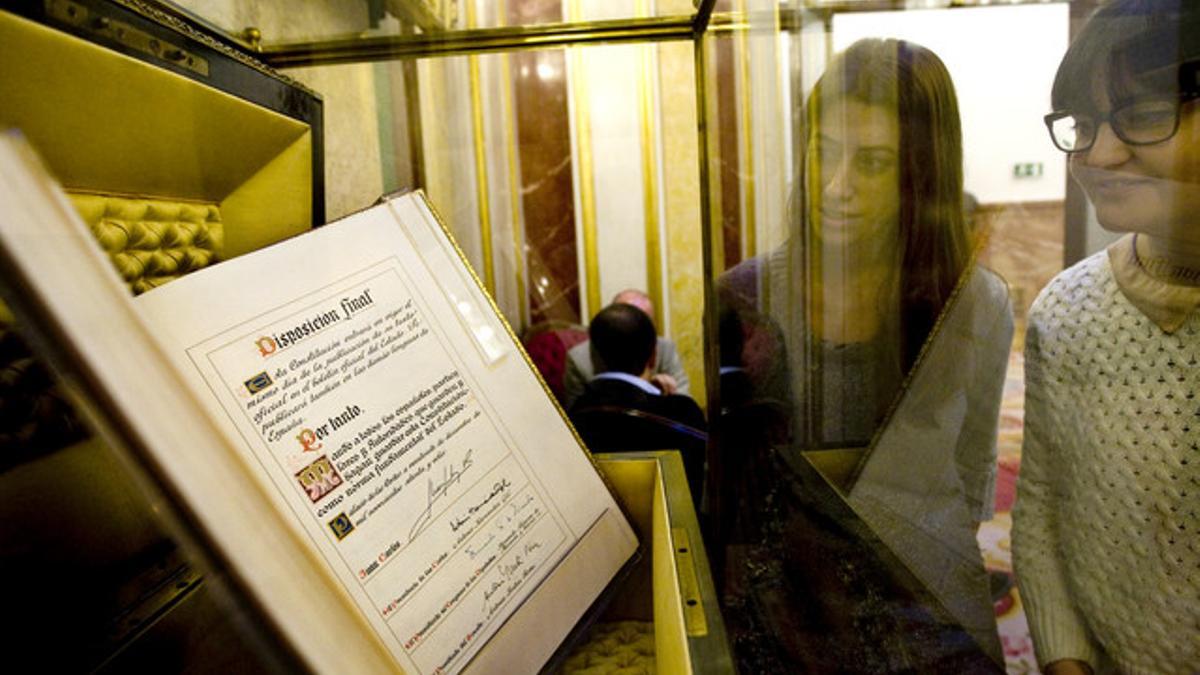 Dos mujeres miran el ejemplar único del texto de la Constitución firmado por el Rey en 1978.