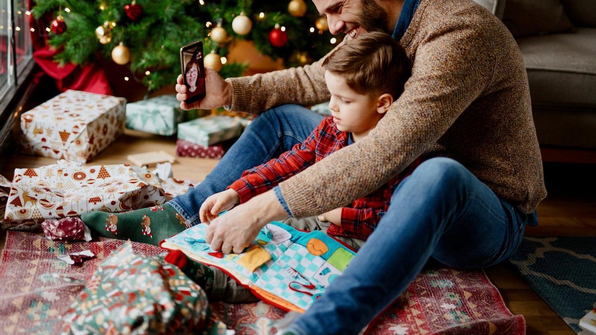 Padre con su hijo abriendo regalos en videollamada