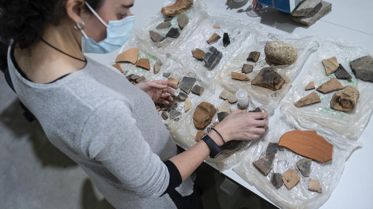 Una investigadora del grupo GEAAT estudia varias piezas en el laboratorio de Arqueología.