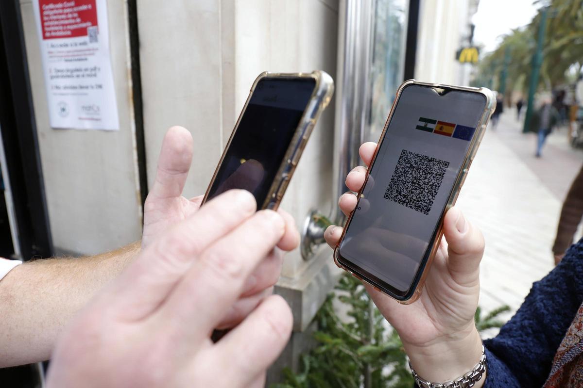 Una persona enseña el pasaporte de vacunación para entrar a un local.