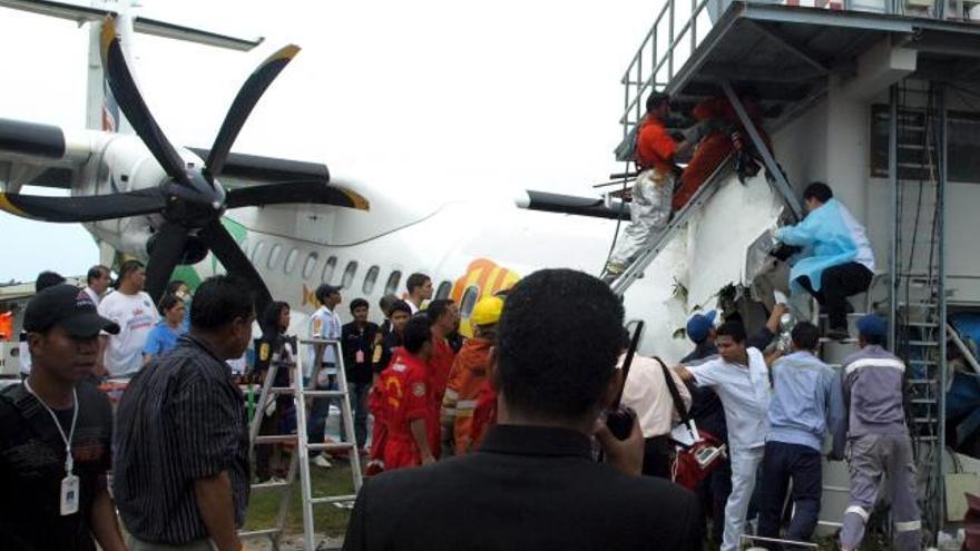 Miembros de los servicios de rescate rodean el avión ATR-72 de la aerolínea Bangkok Airways que se estrelló contra la torre de control en el aeropuerto de Samui (Tailandia).