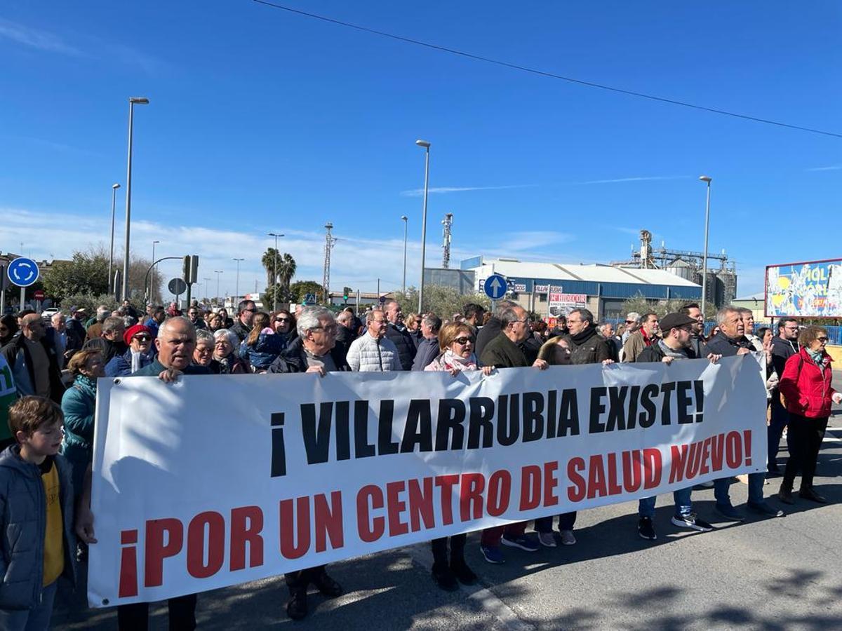Decenas de vecinos con pancartas reivindican en Villarrubia las demandas históricas de la barriada.
