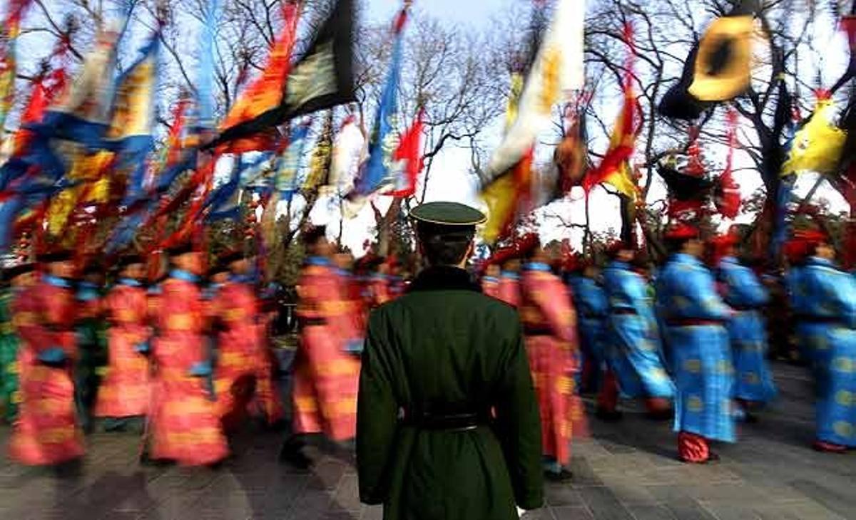 Un grup d’actors vestits de la dinastia Qing desfilen a prop d’un guàrdia de policia paramilitar, durant un assaig per a la celebració del pròxim Any Nou Lunar xinès, al Temple del Cel a Pequín (Xina).