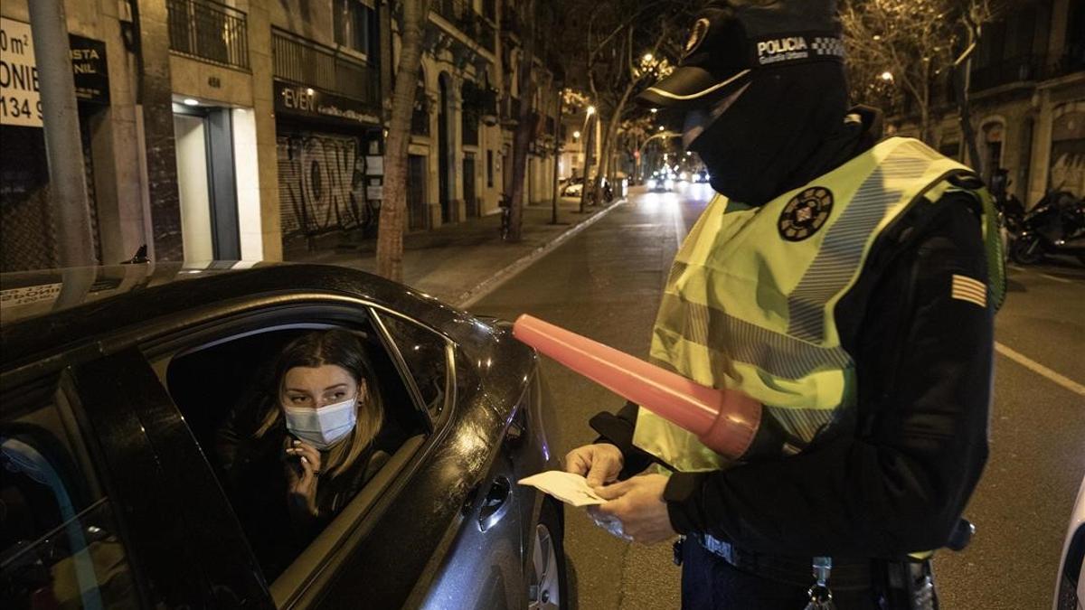 Barcelona 22 01 2021 Reportaje con una patrulla de la Guardia Urbana del Eixample Gracia durante el turno nocturno para detectar fiestas ilegales que incumplen las restricciones de movilidad por el covid y toque de queda  En la foto los agentes de un control de movilidad en el Carrer Valencia identifican y sancionan a personas extranjeras que circulaban en cabify fuera del horario permitido y sin justificacion (22h-6h)  Tambien los registran por si llevan droga  Foto Ferran Nadeu