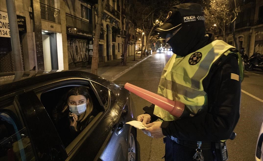 Barcelona 22 01 2021 Reportaje con una patrulla de la Guardia Urbana del Eixample Gracia durante el turno nocturno para detectar fiestas ilegales que incumplen las restricciones de movilidad por el covid y toque de queda  En la foto los agentes de un control de movilidad en el Carrer Valencia identifican y sancionan a personas extranjeras que circulaban en cabify fuera del horario permitido y sin justificacion (22h-6h)  Tambien los registran por si llevan droga  Foto Ferran Nadeu