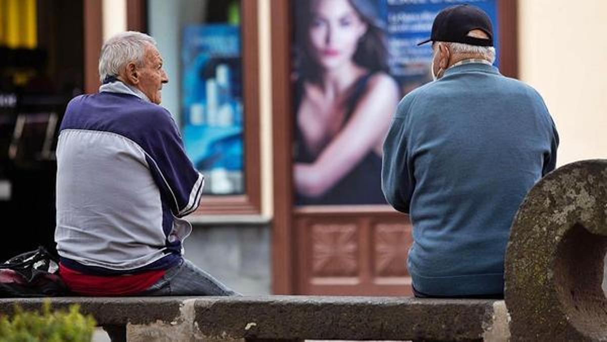 Dos pensionistas canarios charlan en un banco.