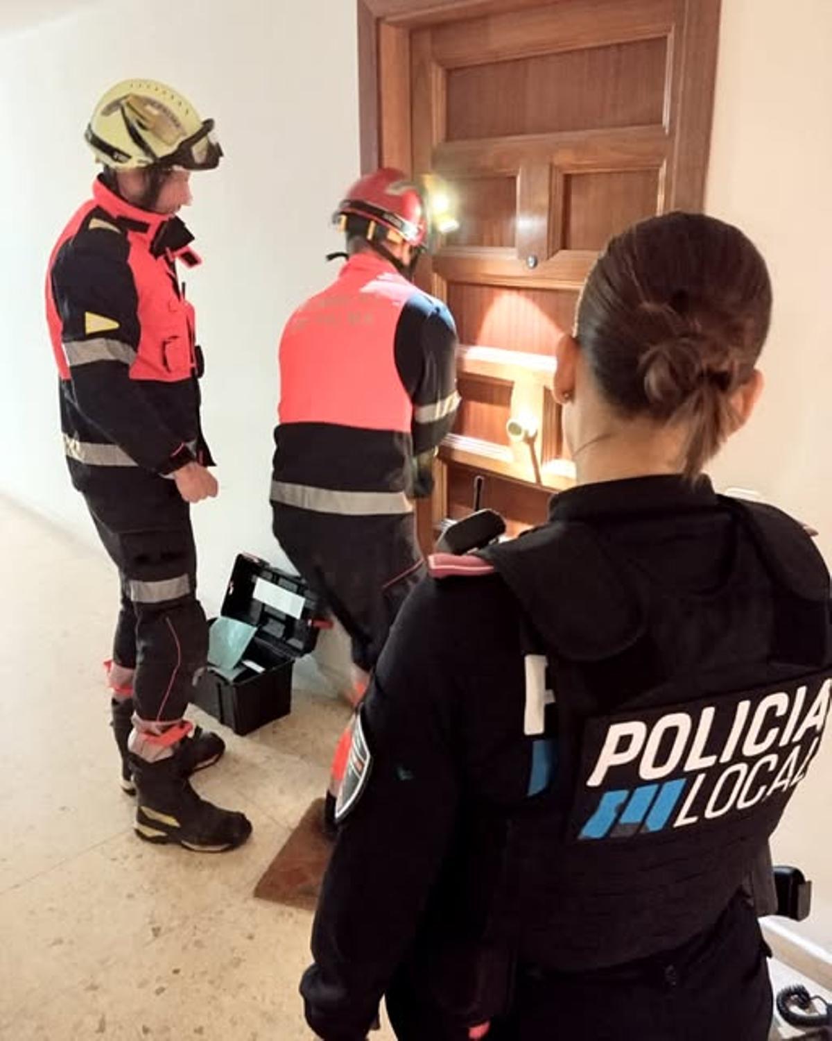 Los bomberos, durante la apertura de la puerta de la casa del anciano.