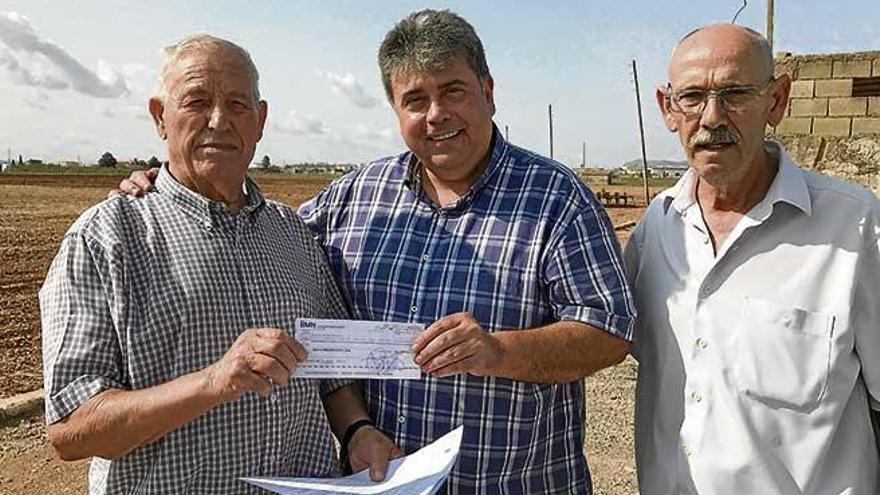 El alcalde (centro) entrega un cheque como pago por la finca.